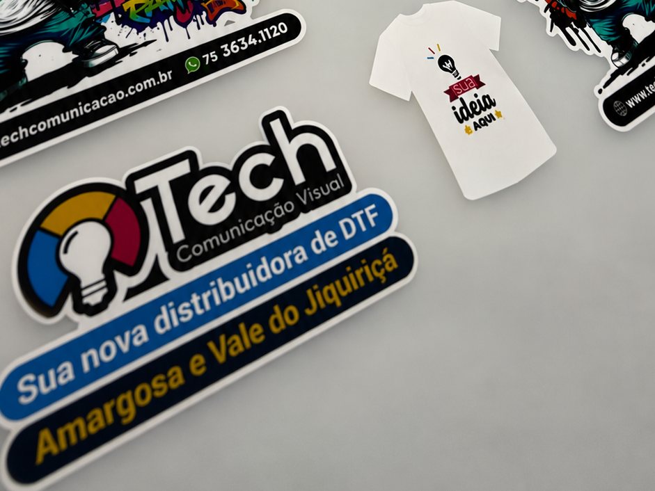Filme DTF impresso na Tech com transfers da marca e camiseta de amostra, prontos para a prensagem